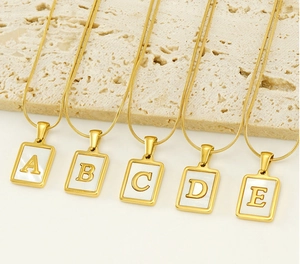 Detail of 18K gold snake chain necklaces with rectangle shell alphabet pendants A to E