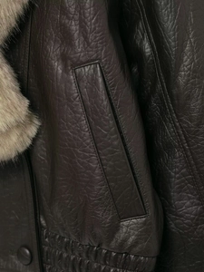 Gros plan sur la veste en cuir marron foncé avec col en fourrure taupe et détails fins
