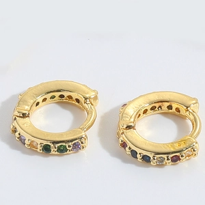 Close-up of gold huggie hoop earrings with multi-color zircon stones on white background