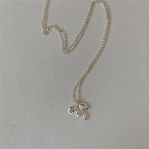 Detailed close-up of a delicate 925 sterling silver bow pendant necklace on white background
