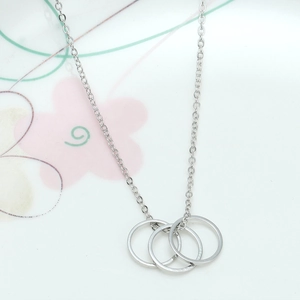 Close-up of silver-tone triple interlocking circle pendant necklace on floral background