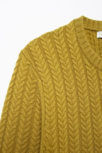 Close-up of yellow knit cardigan showing cable knit texture and neckline size label