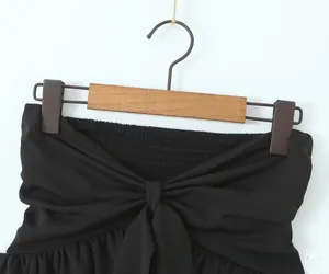 Detailed macro view of black strapless top featuring ruched elastic and a large bow tie