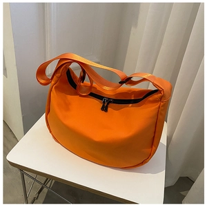 Close-up of bright orange nylon crossbody crescent bag with dual black zippers and wide strap