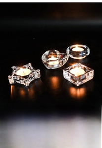 Detail of four geometric glass tealight holders in heart and star shapes with glowing candles