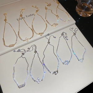 Detail of adjustable zircon bracelets in gold and silver with clover and heart charms