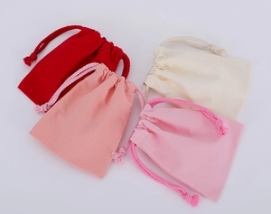 Flat lay of colorful drawstring cotton linen bags in red, pink, and off-white tones