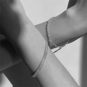 Detail of silver beaded and woven chain bracelets showing intricate metal texture on wrist