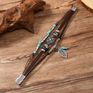 Detail of multi-layer brown leather bracelet with blue beads and silver leaf charm