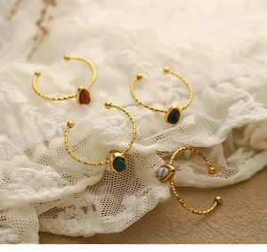Close-up of gold stainless steel rings with red, green, and marble natural stones on lace