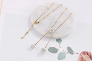 Detail of gold Y-shaped necklace featuring sparkling crystal pavé ball pendants