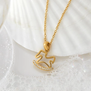 Gold stainless steel rocking horse necklace with sparkling zircons on shell background