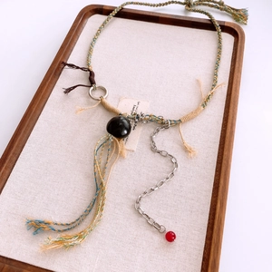 Détail du collier en corde tissée main avec pierre noire et chaîne argentée sur plateau