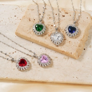Minimalist silver heart necklace with colorful zircon stones on beige stone trays