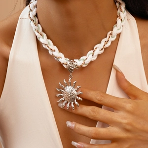 Detail of silver sun pendant on white twisted rope necklace worn by a model