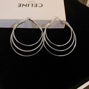 Macro shot of silver triple-layered geometric hoop earrings with polished metallic finish