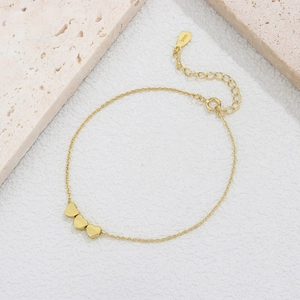 925 silver golden heart bracelet featuring three smooth charms on a textured stone surface