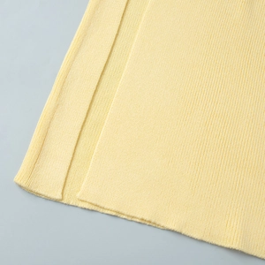 Macro detail of ribbed knit fabric texture and side slit stitching on a yellow midi set