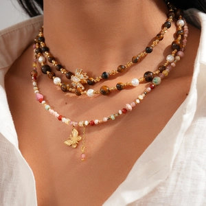 Macro detail of multi-layer tiger eye stone necklace with gold butterfly pendant on model