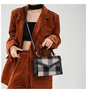 Détail du sac à bandoulière en tweed à carreaux et cuir noir porté par un mannequin en tailleur