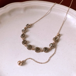 Detail of adjustable gold necklace with nine grey round rhinestones on white ceramic