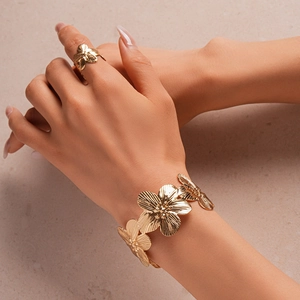 Detail of gold floral cuff bracelet and matching ring set with textured petal patterns