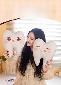 Détail d'un oreiller en peluche en forme de dent avec broderie tenu par un mannequin