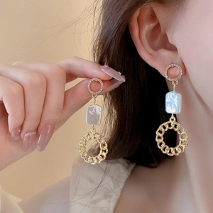 Close-up of gold star earrings with pearls and rhinestones worn by a fashion model