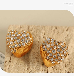 Macro shot of 18K gold-plated heart-shaped stud earrings featuring sparkling white zircons