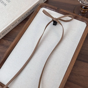 Detailed view of coffee brown faux leather bow clip on a minimalist textured tray