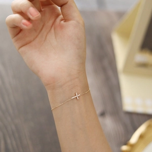 Macro shot of 925 silver cross bracelet with sparkling diamonds on a female wrist