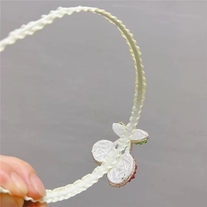 Detail shot of a beige wavy ribbon headband with delicate beaded cherry craftmanship