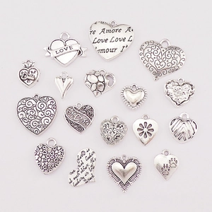 Detailed view of assorted silver alloy heart charms with engraved love quotes and patterns