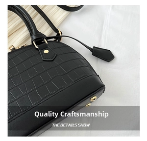 Detail shot of black crocodile embossed shell bag showing gold rivets and premium stitching