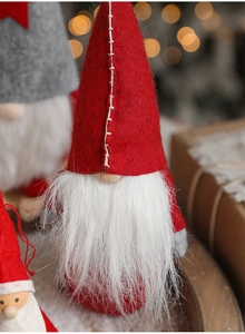 Close-up of red and grey Christmas gnome dolls with white beards and festive lights