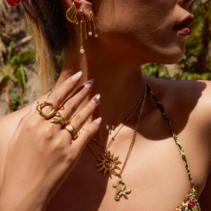 Gold plated stainless steel jewelry set with pearls and sun pendants on a model