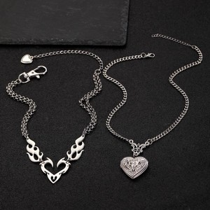 Detail view of vintage silver locket with eagle engraving and flame heart necklace