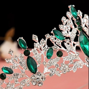 Macro detail of emerald green rhinestones set in a silver baroque tiara floral base