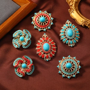 Detailed close-up of ethnic style brooches with turquoise beads on brown satin fabric