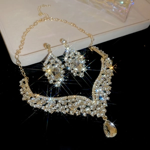 Macro shot of luxury gold V-shaped necklace and drop earrings with sparkling rhinestones