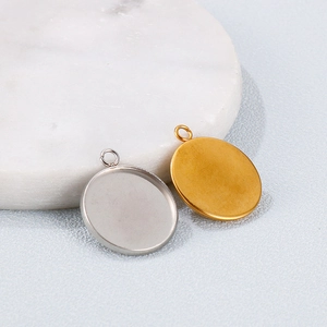 Round gold and silver stainless steel pendant base trays for jewelry making on marble surface