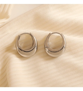 Detailed macro shot of thick silver-tone geometric earrings on soft ribbed fabric