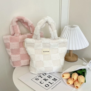 Detail of pink and beige plush checkerboard tote bag on a white table with tulip