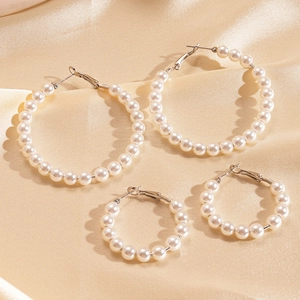 Elegant pearl hoop earrings set on champagne satin background with silver metal clasps