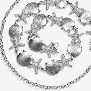 Detailed close-up of silver waist chain with seashells, starfish and pearl charms