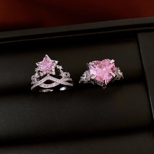 Makroaufnahme von Silberringen mit rosa Stern und Herz-Zirkonia auf schwarzem Leder