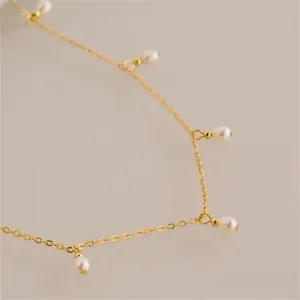 Close-up of golden titanium steel chain with five elegant white pearls in detail view