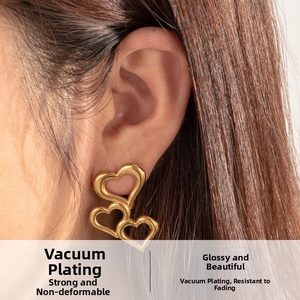 Detailed close-up of golden triple-heart layered earrings worn by a model