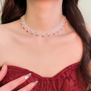Detail of beaded choker necklace with white lace mesh beads and red drop beads on a model