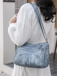 Vintage blue washed crossbody bag with multi-zipper pockets and rivet details on model